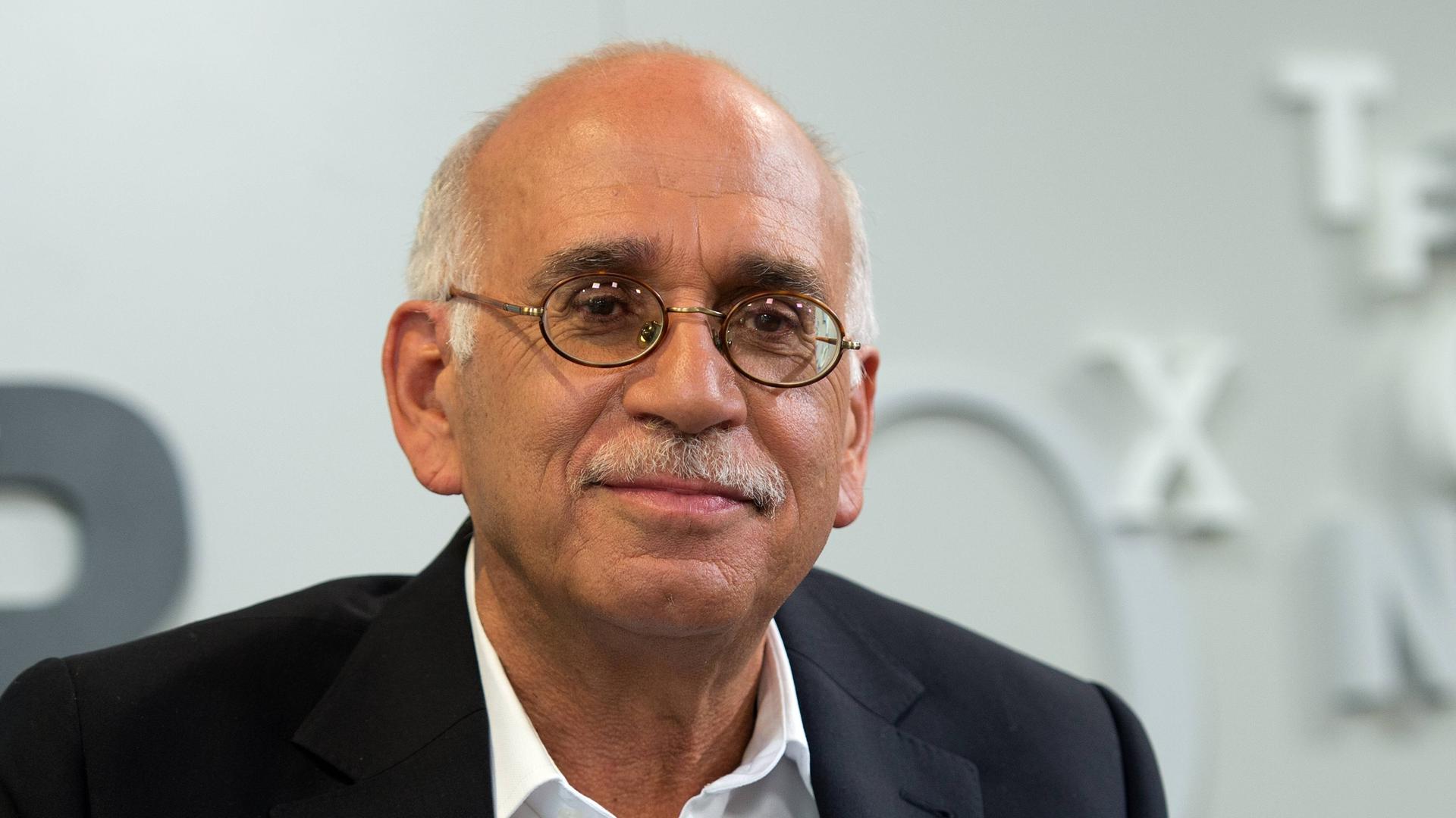 Erich Follath sitzt auf einer Bühne und schaut ins Publikum.