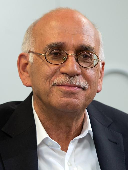 Erich Follath sitzt auf einer Bühne und schaut ins Publikum.