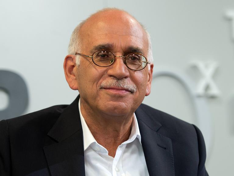 Erich Follath sitzt auf einer Bühne und schaut ins Publikum.