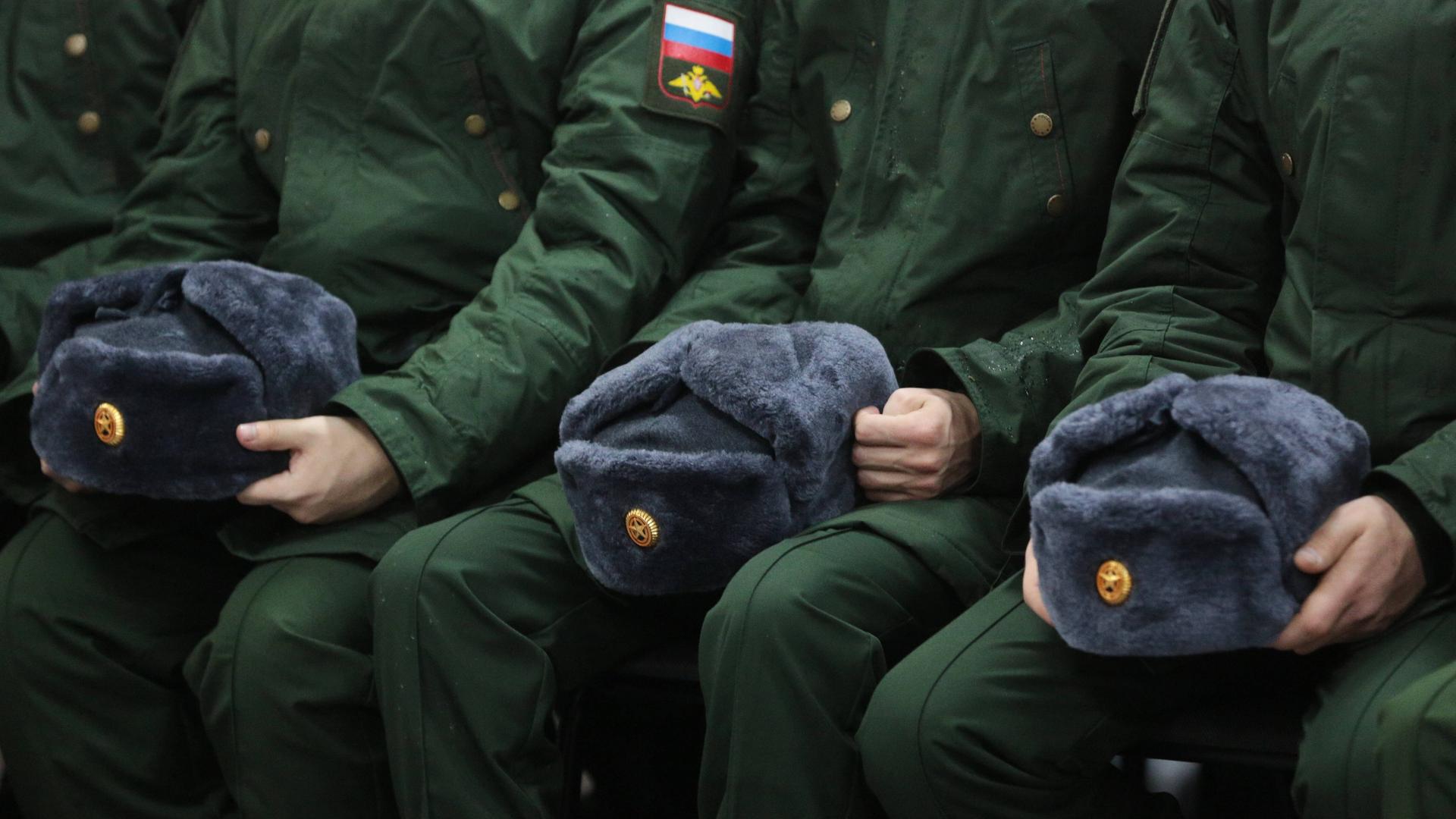 Zu sehen sind Mützen und Uniformen russischer Soldaten.