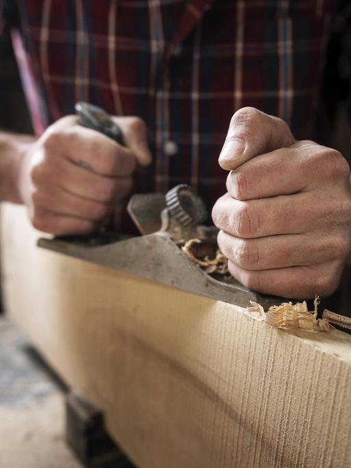 Mann arbeitet in einer Holzwerkstatt.