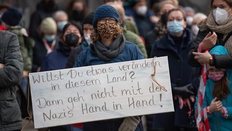 Teilnehmende einer Demonstration gegen Querdenker. Eine Frau hält ein Anti-Nazi-Schild hoch.