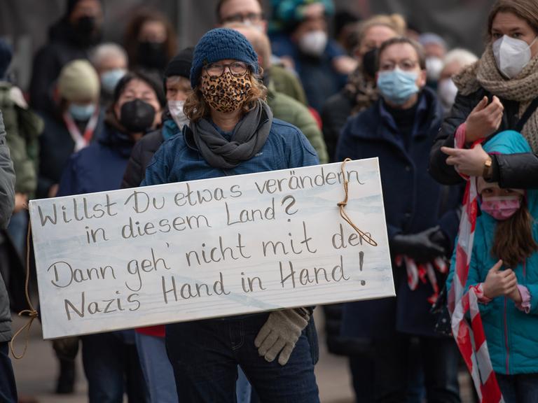 Teilnehmende einer Demonstration gegen Querdenker. Eine Frau hält ein Anti-Nazi-Schild hoch.