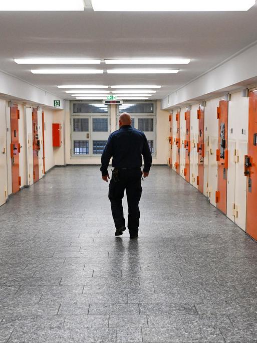 Ein Vollzugsbeamter geht in der Zugangsabteilung der Justizvollzugsanstalt Moabit in Berlin an Zellentüren vorbei.