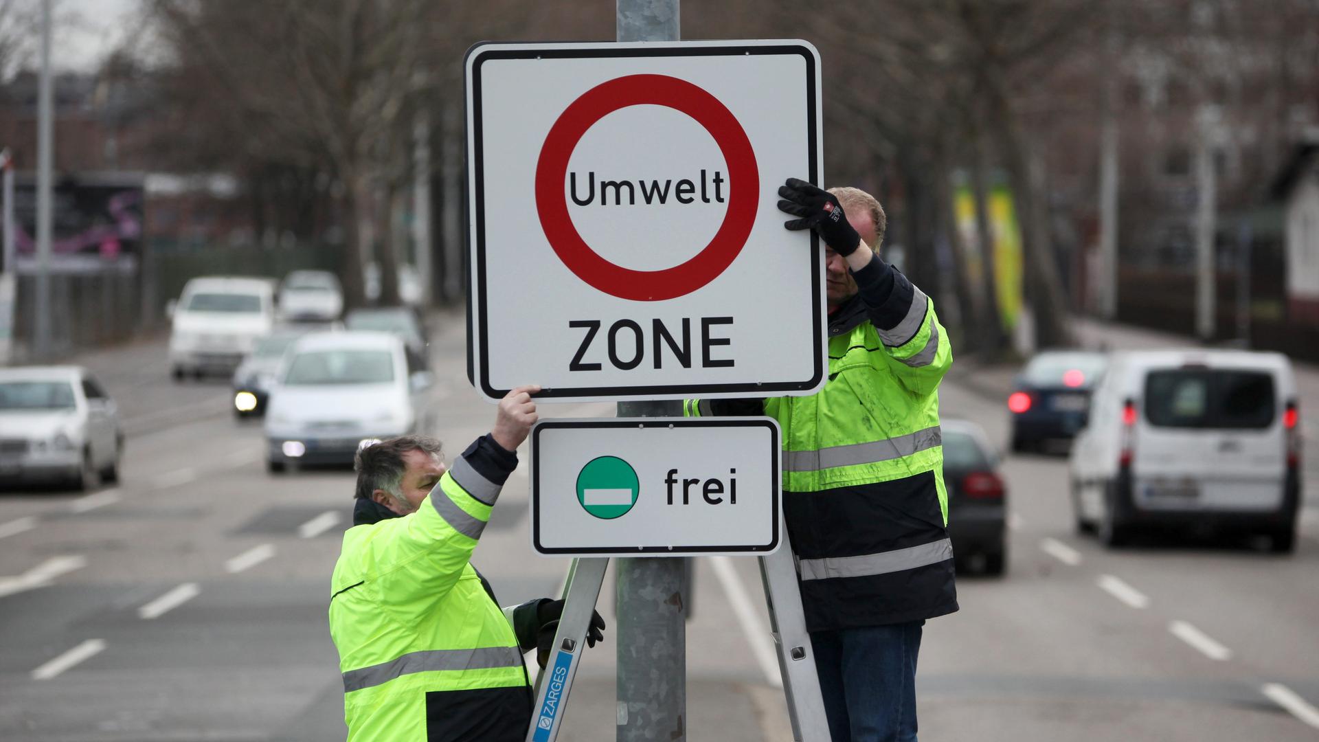 Ein Hinweis-Schild für eine Umweltzone in Mainz. Arbeiter bringen das Schild an.