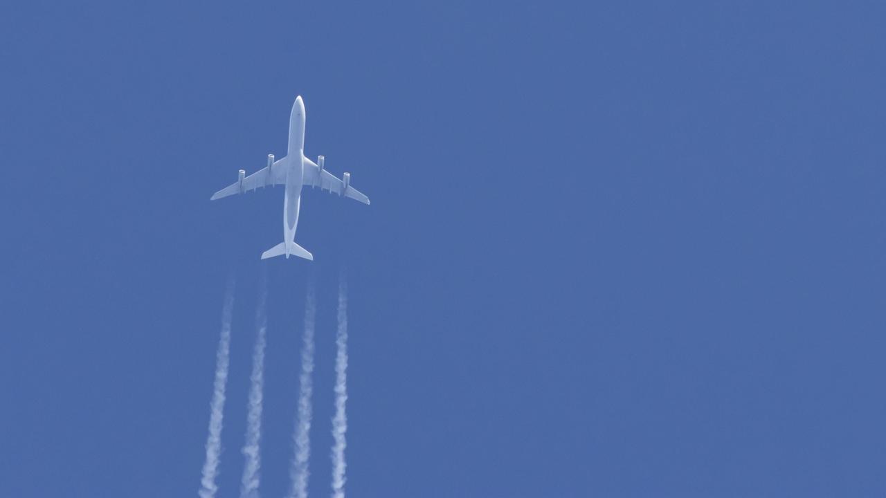 Ein Flugzeug in einem blauen Himmel mit Kondensstreifen dahinter