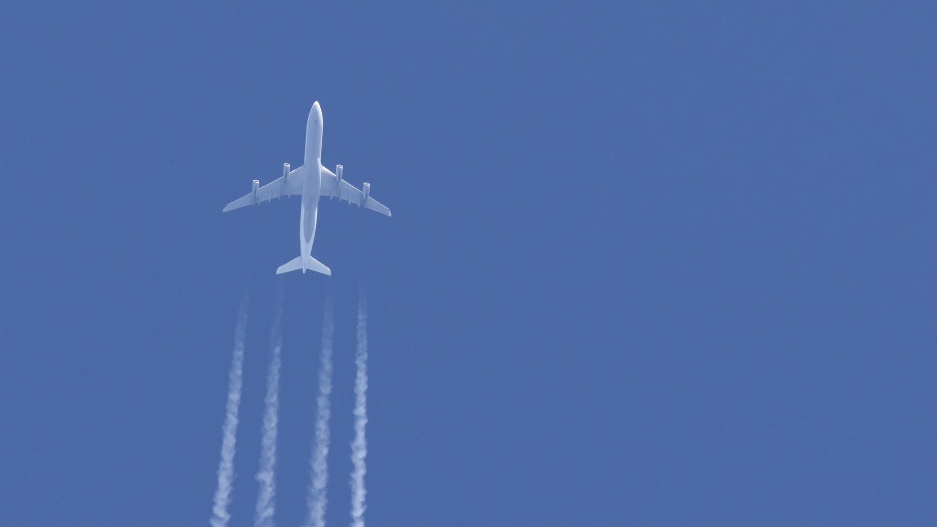 Ein Flugzeug in einem blauen Himmel mit Kondensstreifen dahinter Ein Flugzeug in einem blauen Himmel mit Kondensstreifen dahinter