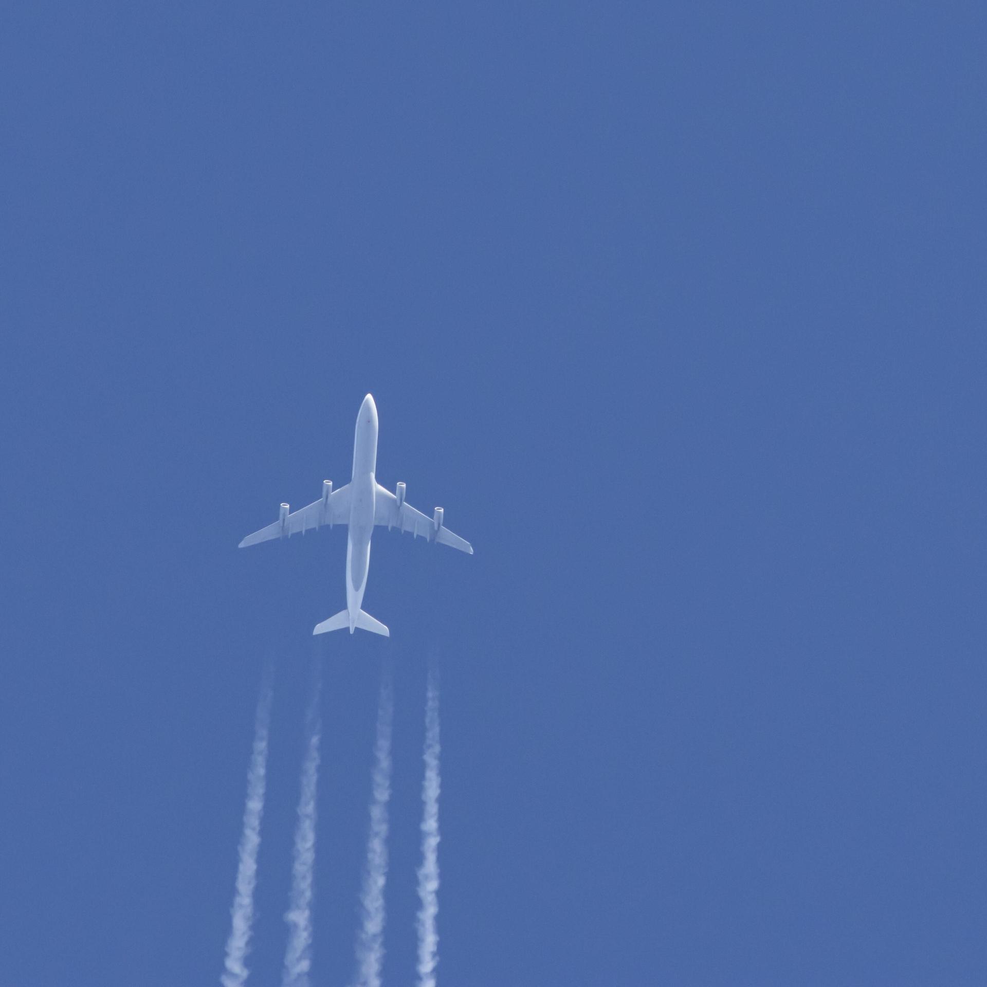 Ein Flugzeug in einem blauen Himmel mit Kondensstreifen dahinter