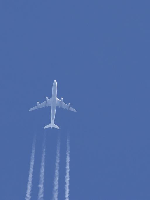 Ein Flugzeug in einem blauen Himmel mit Kondensstreifen dahinter
