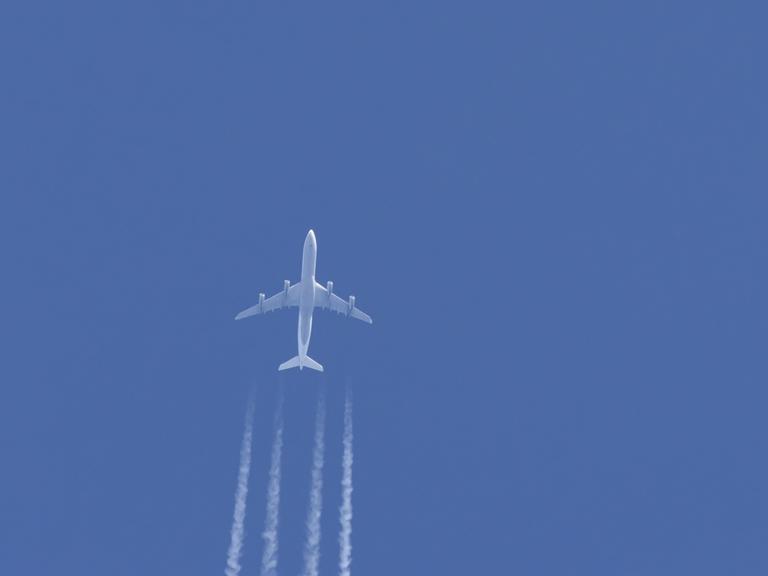 Ein Flugzeug in einem blauen Himmel mit Kondensstreifen dahinter