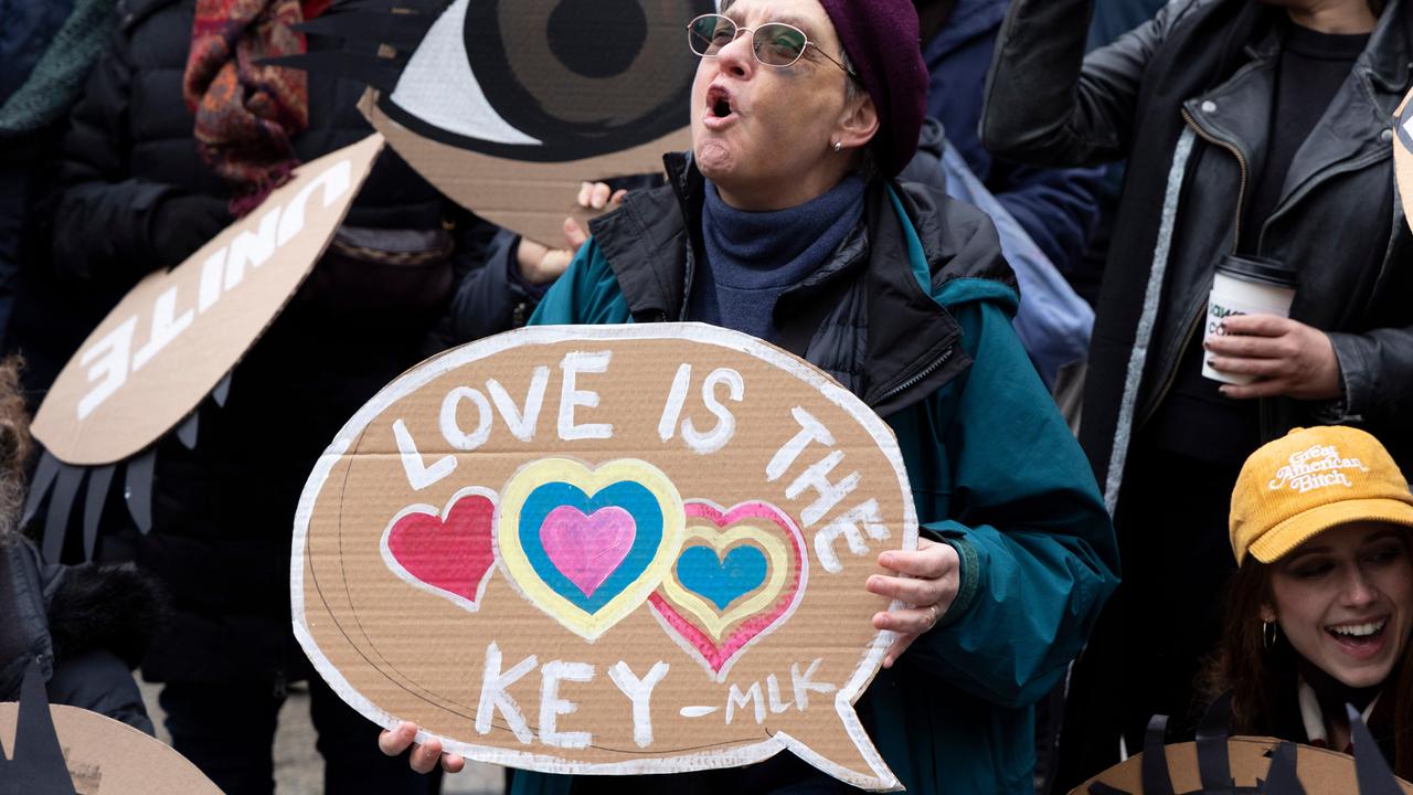 Eine Protestierende steht zwischen Menschen, ruft und hält ein Schild, auf dem steht: "Love is the key".