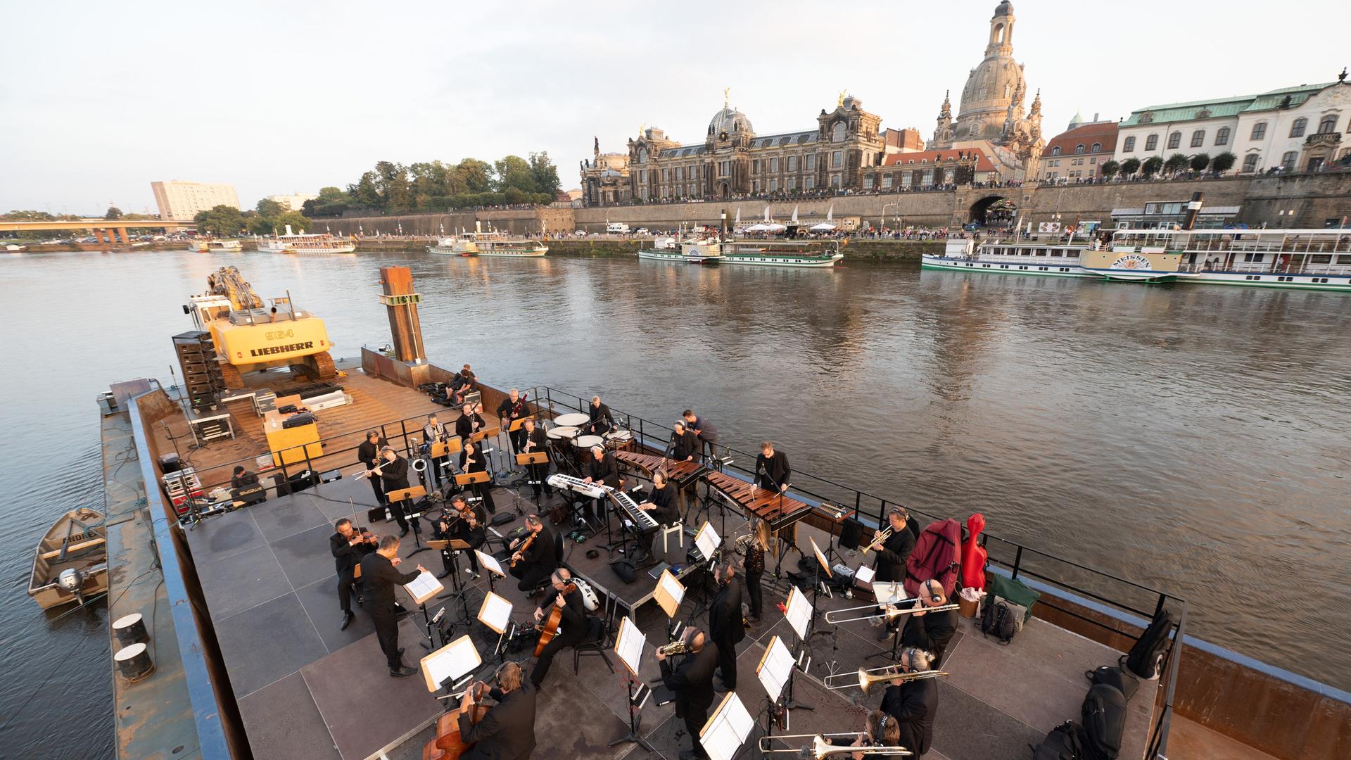 Musiker der Dresdner Sinfoniker stehen während des Konzerts «Elbkarawane» auf einem Schubverband vor der Kulisse der Dresdner Altstadt mit der Frauenkirche.