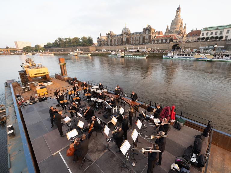 Musiker der Dresdner Sinfoniker stehen während des Konzerts «Elbkarawane» auf einem Schubverband vor der Kulisse der Dresdner Altstadt mit der Frauenkirche. Musiker der Dresdner Sinfoniker stehen während des Konzerts «Elbkarawane» auf einem Schubverband vor der Kulisse der Dresdner Altstadt mit der Frauenkirche.