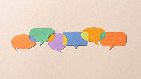 Verschiedenfarbige Papiersprechblasen, die durch andere Farben miteinander verbunden sind.