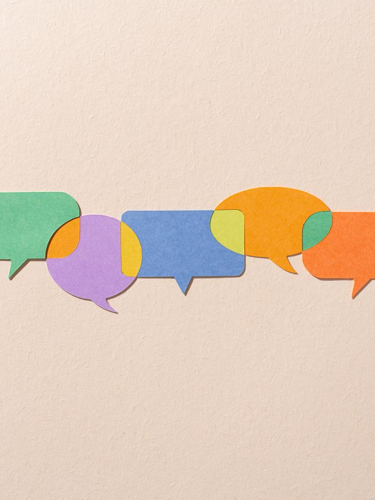 Verschiedenfarbige Papiersprechblasen, die durch andere Farben miteinander verbunden sind.