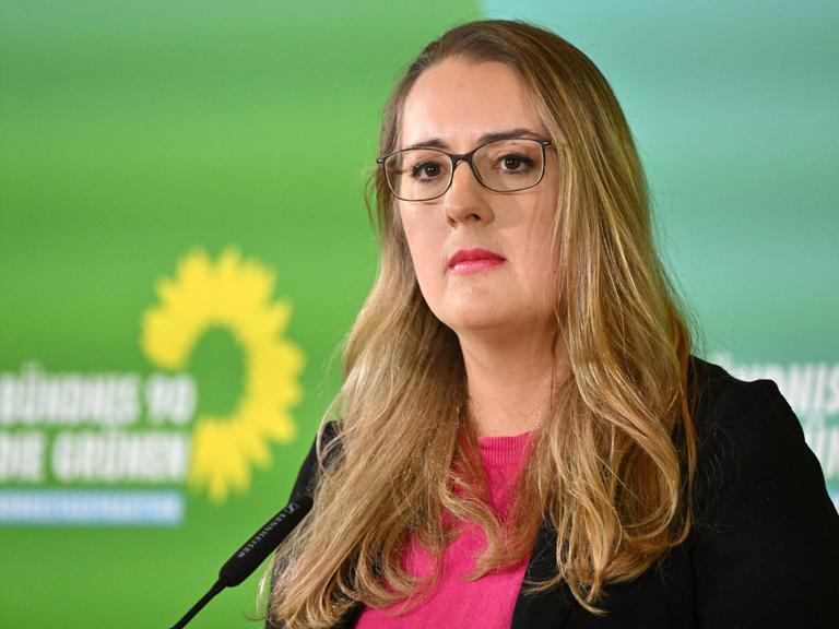 Ein Frau mit langen Haaren, Brille und in pinkem Oberteil schaut konzentriert. Es ist Katharina Dröge, Bundestags-Fraktionsvorsitzende von Bündnis 90/Die Grünen, die während der Klausur der Bundestagsfraktion Bündnis 90/Die Grünen ein Statement gibt.