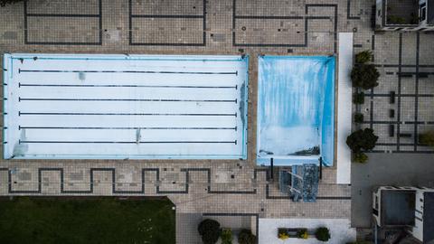 Vogelperspektive auf ein leeres Freibad mit abgelassenen Schwimmbecken.