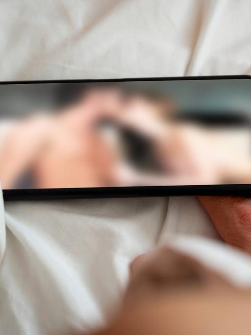 Eine Person schaut sich auf einem Smartphone eine Porno-Internetseite an