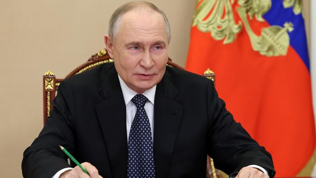 Russlands Präsident Wladimir Putin sitzt bei einem Treffen an einem Tisch, beide Unterarme aufgestützt, in der linken Hand einen Bleistift mit der Spitze nach oben.