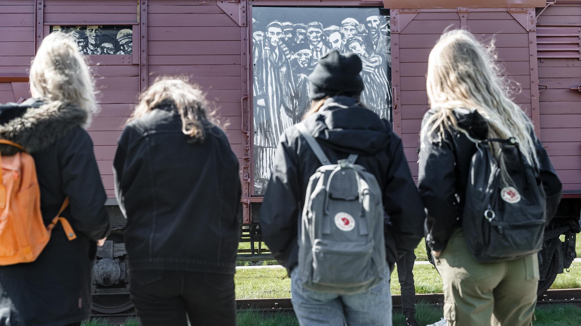Schülerinnen betrachten einen historischen Reichsbahnwaggon im ehemaligen Lagerbahnhof des Konzentrationslagers Neuengamme