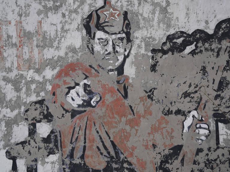 Ein verwittertes Wandbild mit einem sowjetischen Soldaten.