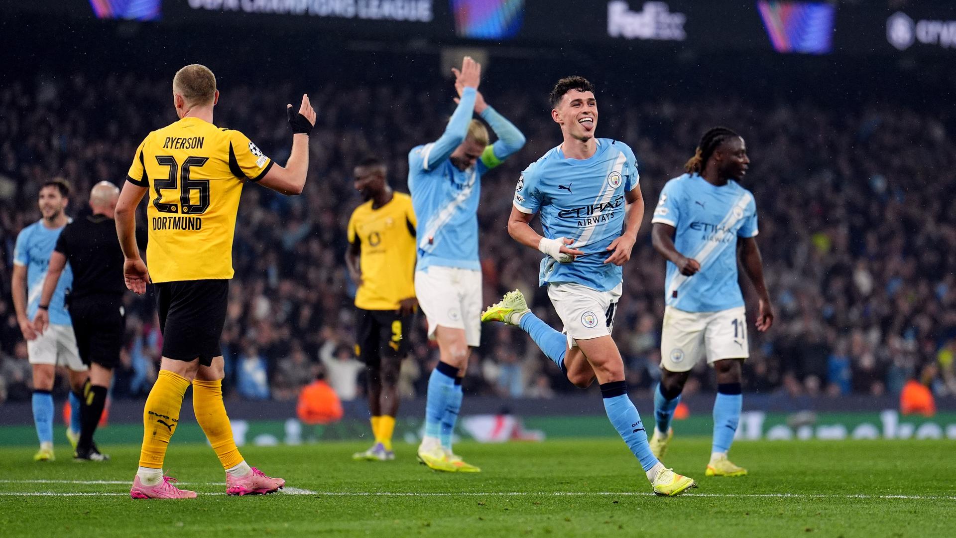 Phil Foden feiert seinen Treffer für Manchester City im Spiel der UEFA Champions League gegen Borussia Dortmund. Im Hintergrund sieht man frustierte Dortmunder Spieler.
