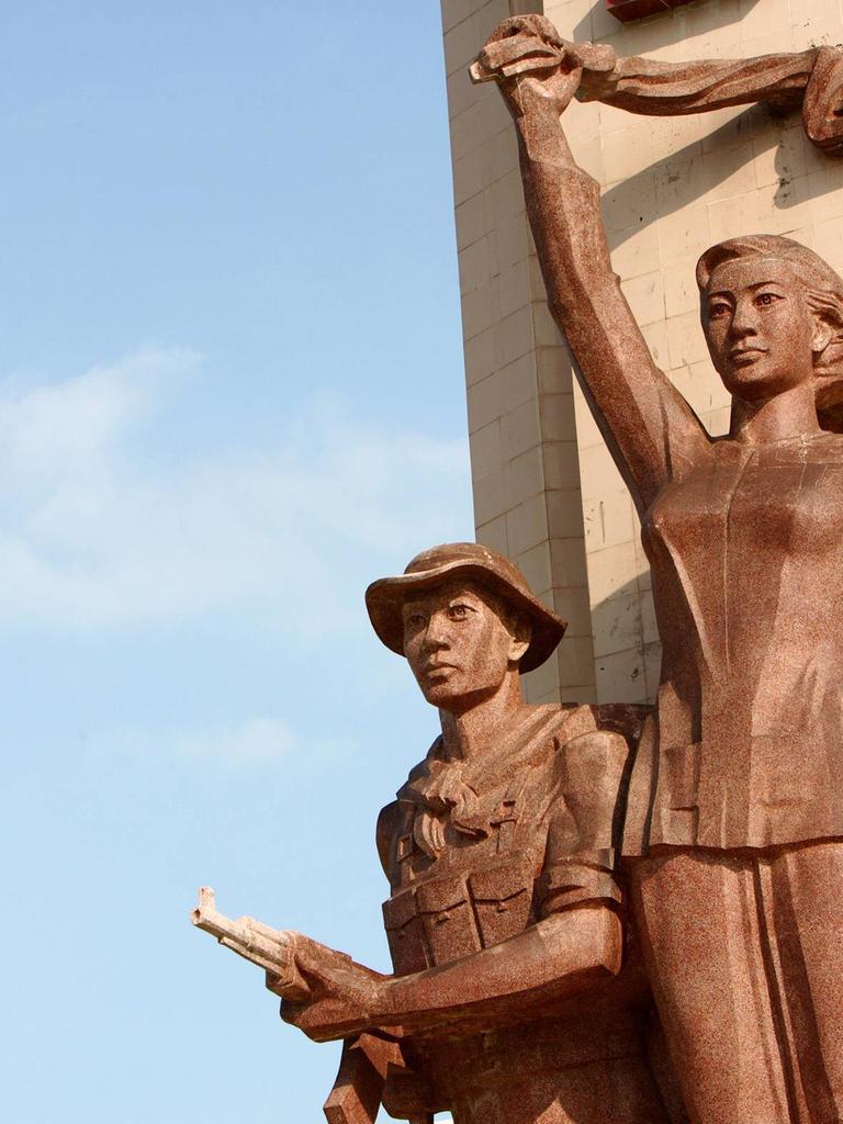 Ein vietnamesisches Märtyrerdenkmal auf einem Heldenfriedhof für die vietnamesischen Gefallenen des Vietnamkrieges in Can Tho. Die Statue einer Frau hält ein Tuch über ihrem Kopf. Darunter die Statue eines Mannes in Soldaten-Uniform mit Hut und Waffe.