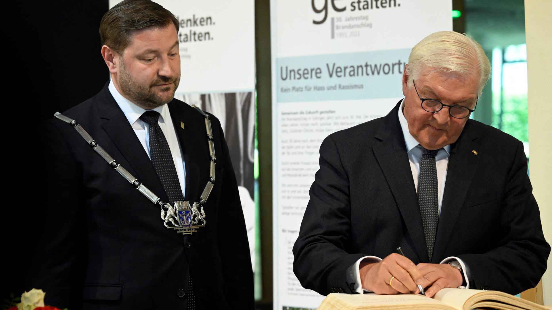 Bundespräsident Frank-Walter Steinmeier (rechts) schreibt ins Goldene Buch der Stadt Solingen. Neben ihm steht Solingens Bürgermeister Tim Kurzbach.