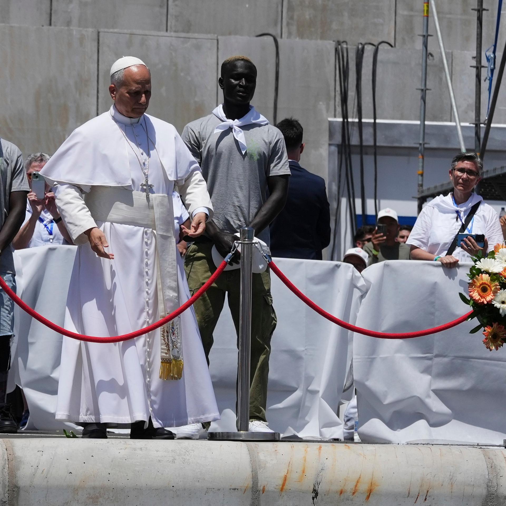Arguineguin: Papst Leo XIV. wirft einen Blumenstrauß ins Meer, flankiert von Migranten, während eines Treffens mit Organisationen, die mit Migranten arbeiten.