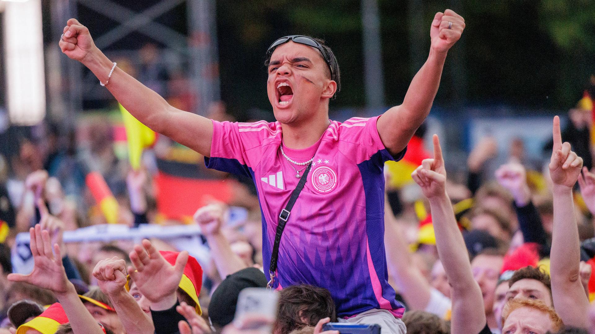 Fans jubeln. Einer von ihnen trägt das pinke Trikot.