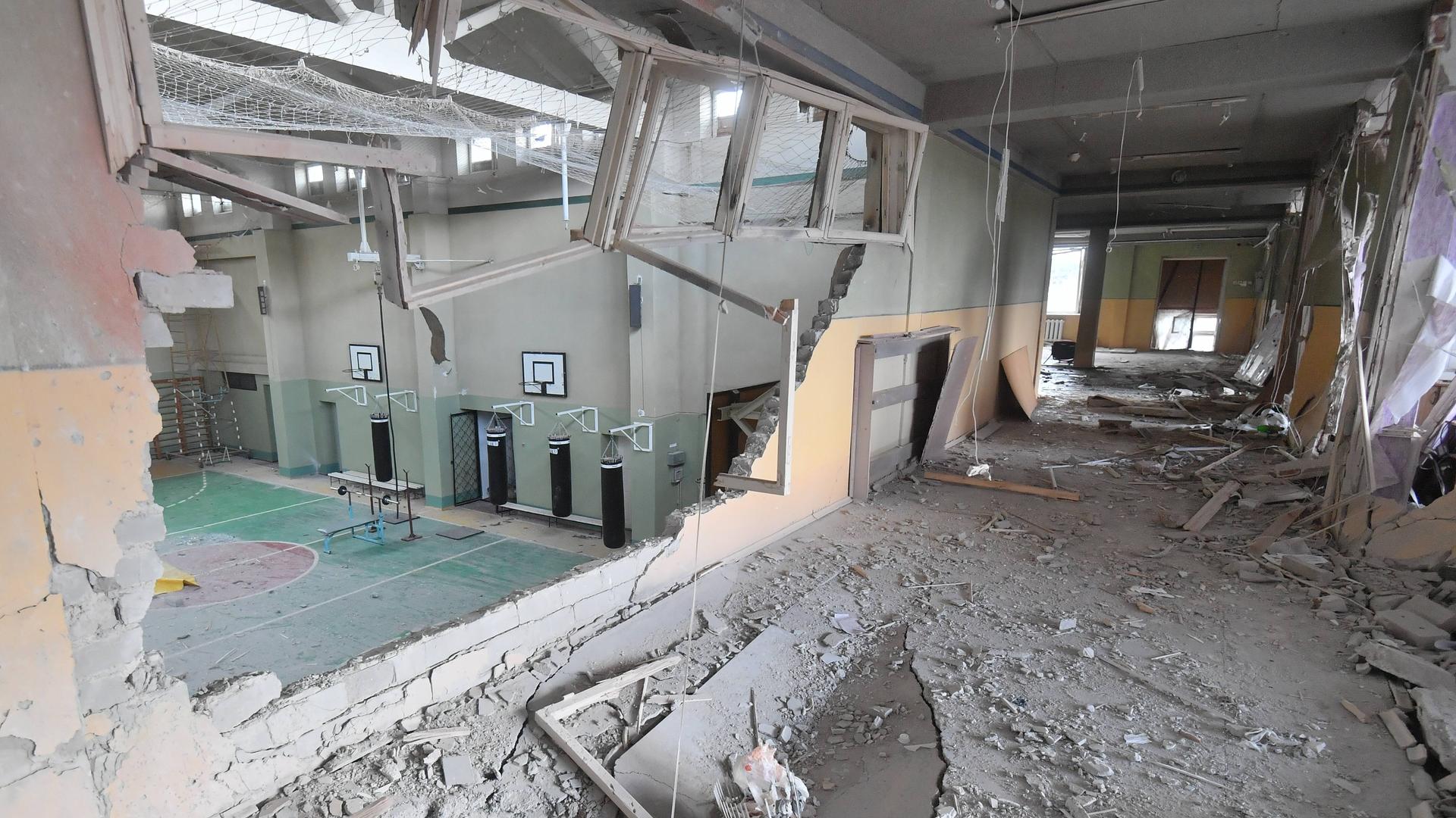 Durch ein Loch in der Wand ist die zerstörte Turnhalle einer Schule zu sehen.