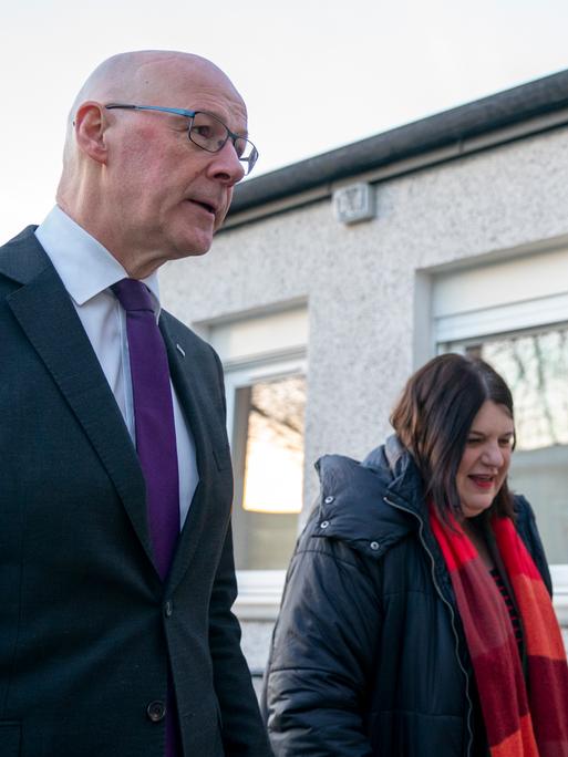 Der schottische Ministerpräsident John Swinney und die Vorsitzende des Stadtrats von Glasgow, Susan Aitken stehen vor einer Hauswand mit der Aufschrift "The Thistle".