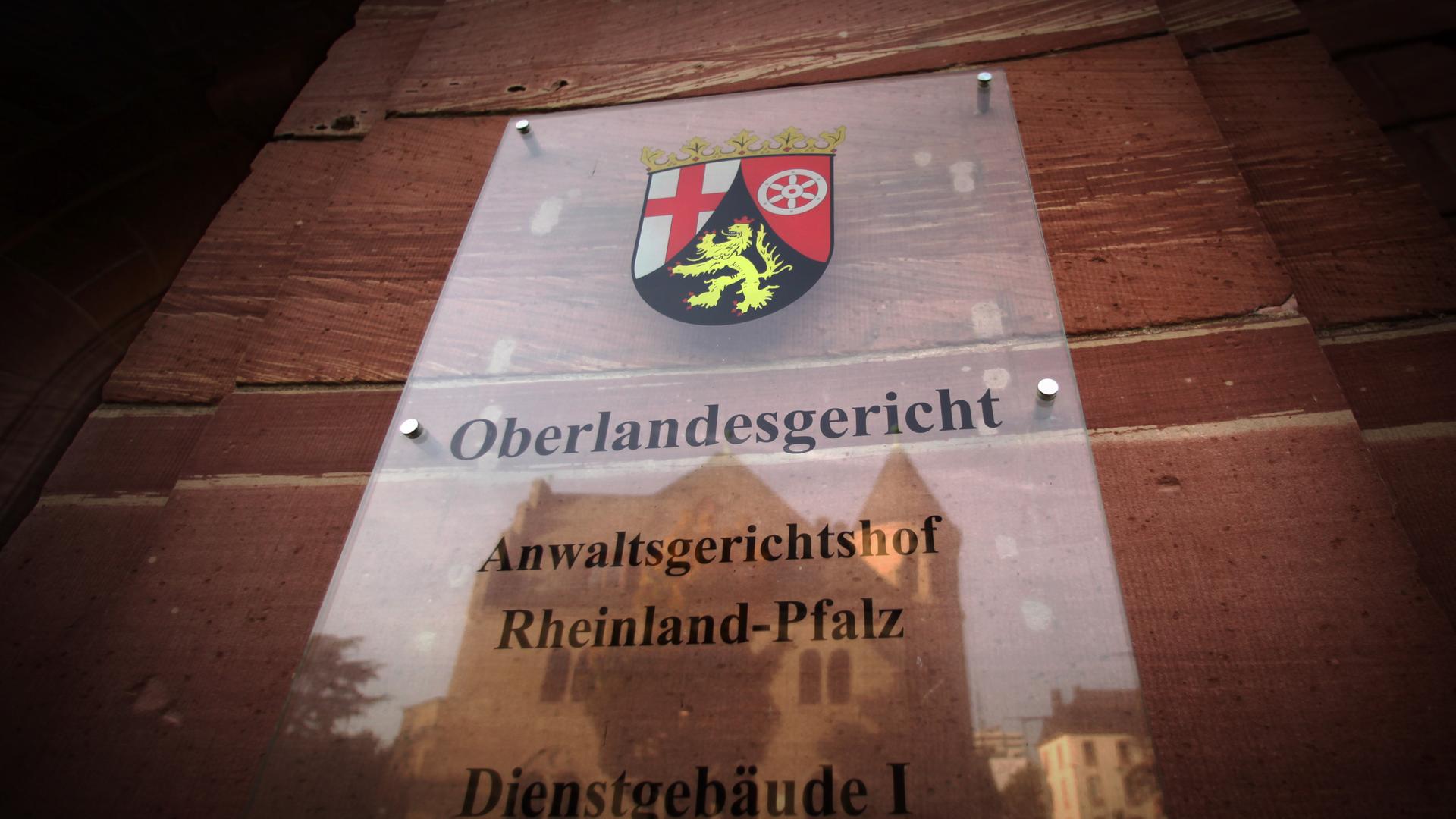 Im Türschild des Oberlandesgerichts in Koblenz spiegelt sich in ein weiteres Verwaltungsgebäude der Rechtsbehörde.