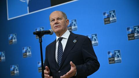 Scholz steht hinter einem Mikrofon und spricht zu Pressevertretern.