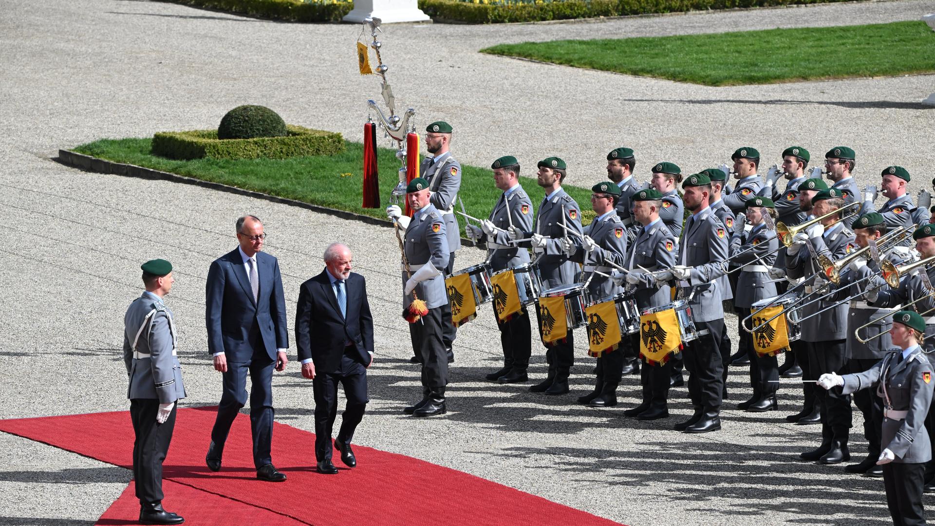 Bundeskanzler Merz und Brasiliens Präsidenten Lula schreiten über einen roten Teppich. Lula wird von Soldaten der Bundeswehr mit militärischen Ehren empfangen. 