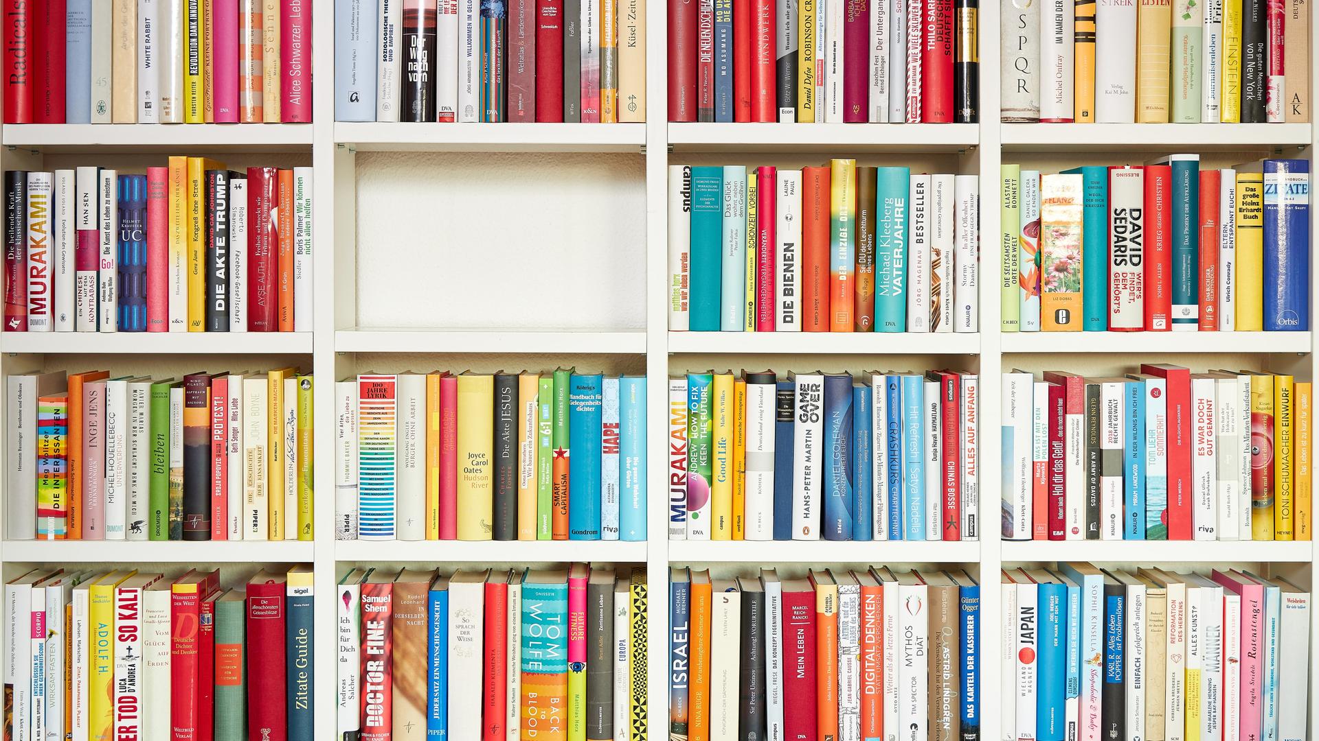 Ein weißes Regal gefüllt mit Büchern - einzig das mittlere Fach ist komplett leer