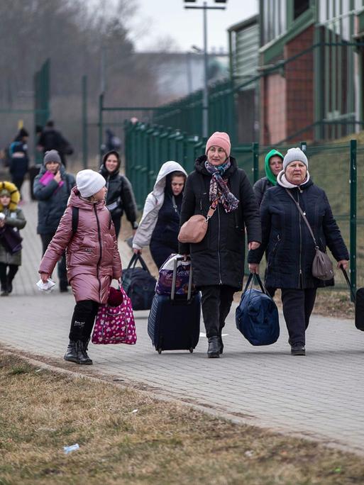 Frauen und Kinder mit Gepäck überqueren von der Ukraine aus die polnische Grenze in Medyka.
