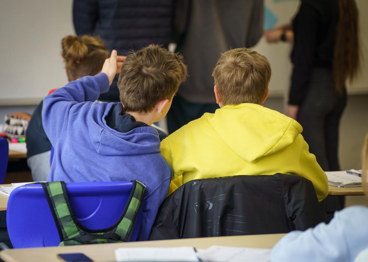 Zwei aus der Ukraine geflüchtete Schüler sitzen in einem Gymnasium in Rheinland-Pfalz an einem Tisch. Der eine (l) trägt einen blauen Pulli, der andere (r) einen gelben - die Nationalfarben der Ukraine.