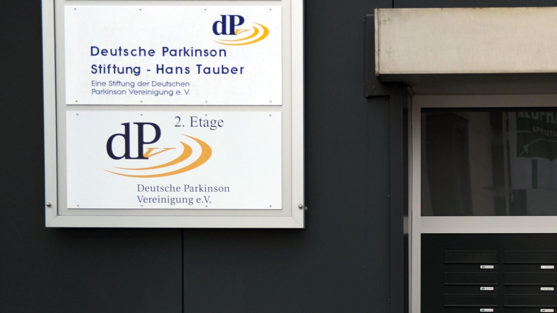 An einem Geschäftshaus in Neuss hängen die Schilder der Deutschen Parkinson Vereinigung e.V und der Hans-Tauber-Stifung der Deutschen Parkinson Vereinigung (dPV).