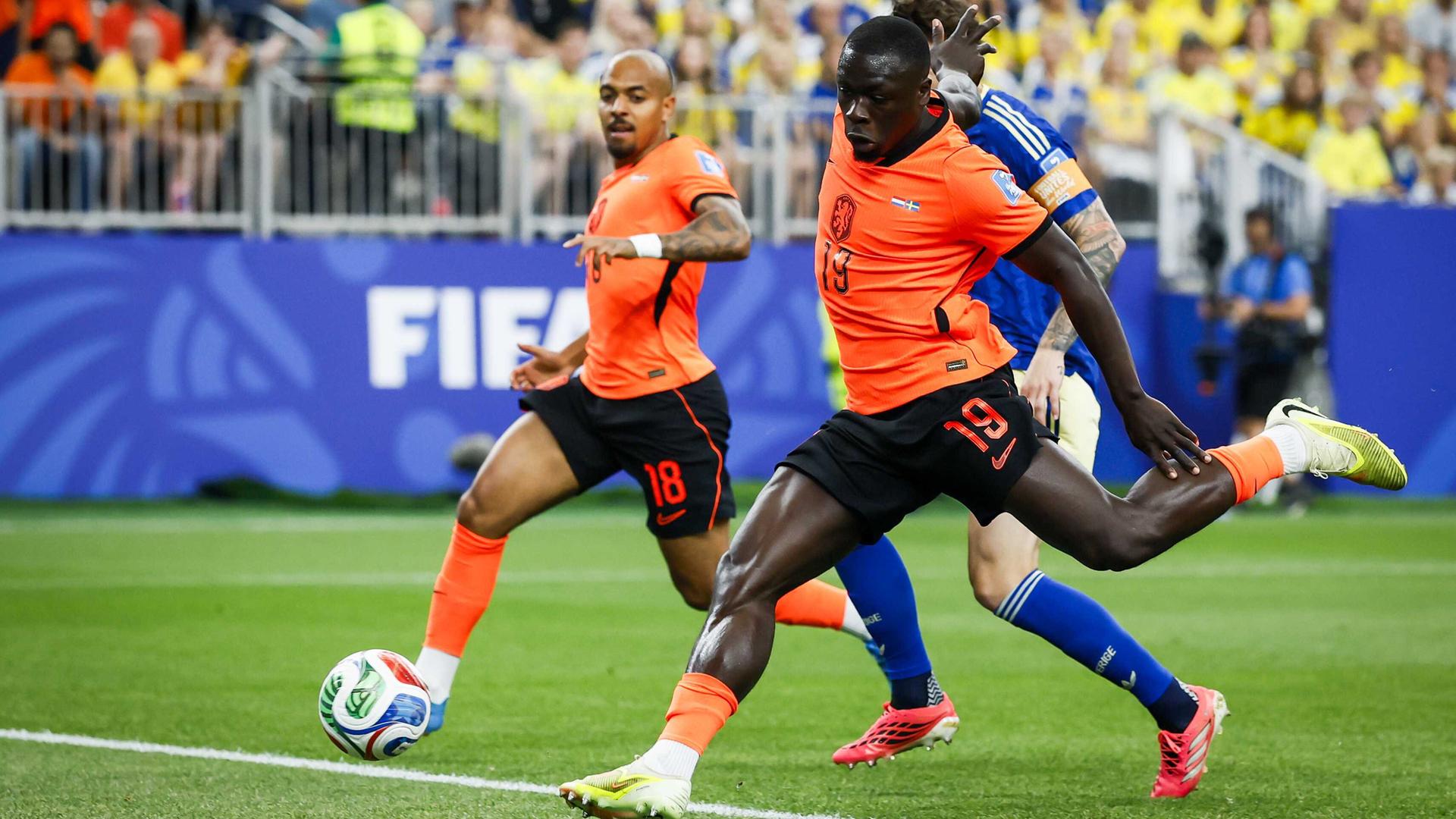Brian Brobbey schießt den Ball ins Tor. Er trägt das orange Trikot der Niederlande. Seine Beine sehen sehr muskulös aus. Brian Brobbey schießt den Ball ins Tor. Er trägt das orange Trikot der Niederlande. Seine Beine sehen sehr muskulös aus.