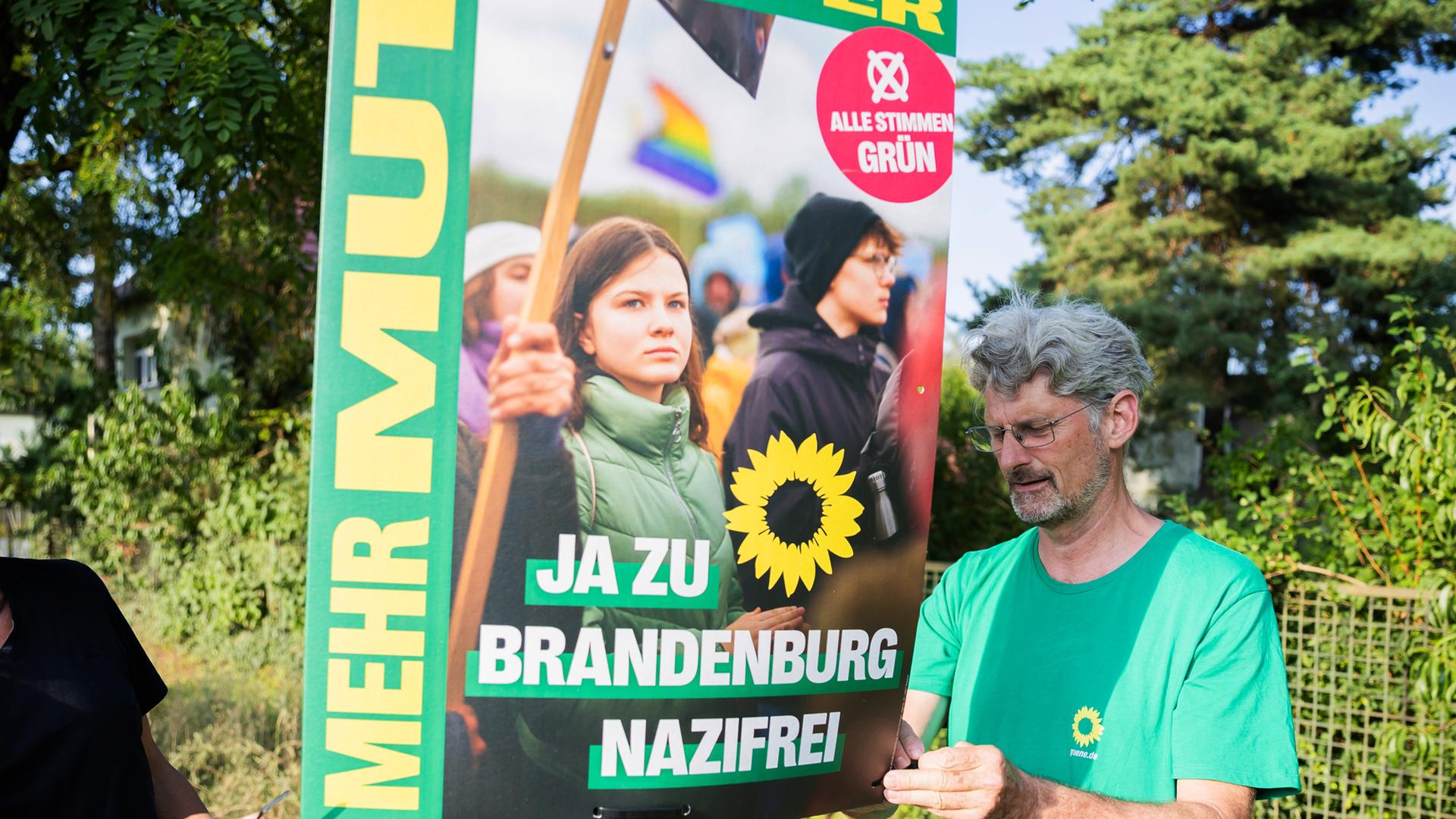 Mitglieder des Brandenburger Landtags hängen ein Wahlplakat auf, nachdem ein Wahlhelfer der Grünen in Hohen Neuendorf angegriffen und beraubt worden war, 14.08.2024.