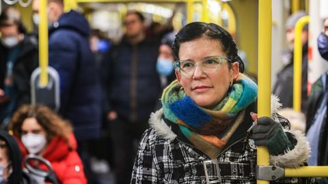 Eine Frau steht ohne Maske in der U-Bahn und hält sich an einer gelben Stange fest. Im öffentlichen Nahverkehr von Nordrhein-Westfalen gibt es keine Maskenpflicht mehr.