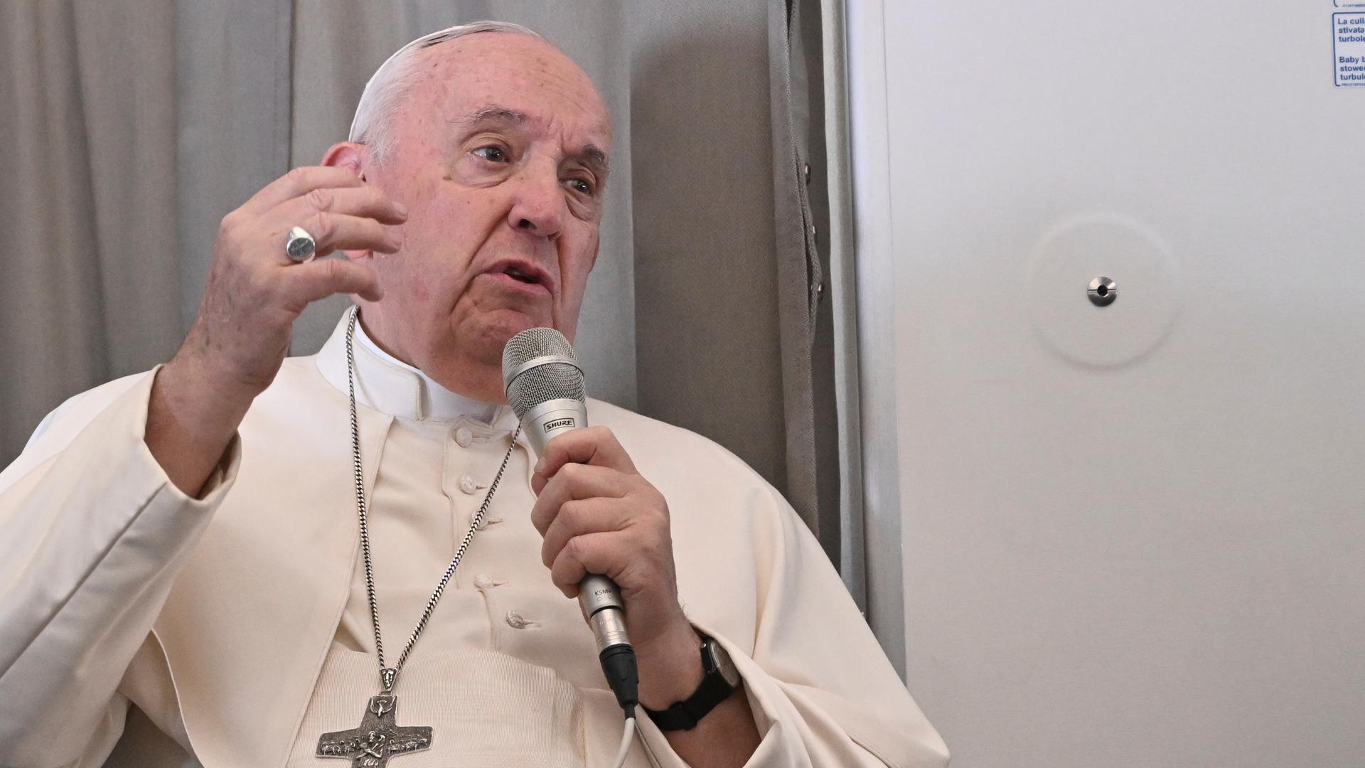 Papst Franziskus spricht in ein Mikrofon. Papst Franziskus spricht in ein Mikrofon.