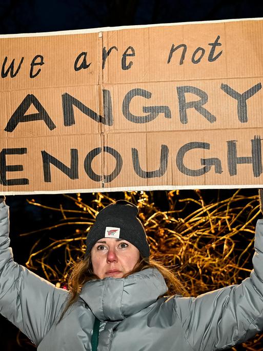 Eine Frau in Winterkleidung hält das Schild mit der Aufschrift "We are not angry enough" hoch Eine Frau in Winterkleidung hält das Schild mit der Aufschrift "We are not angry enough" hoch