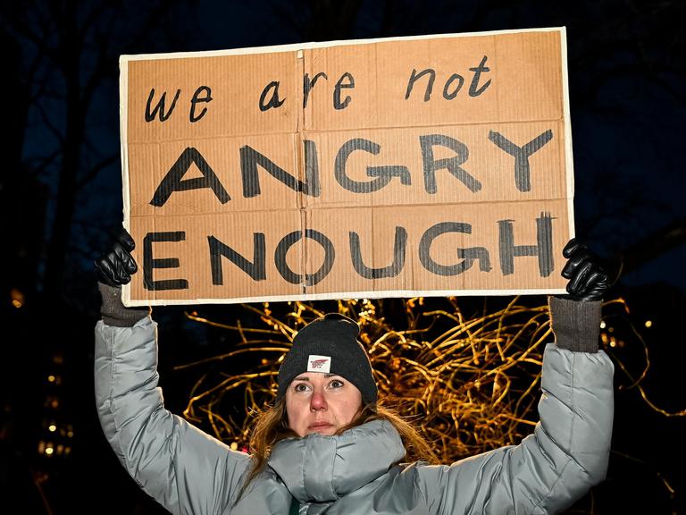Eine Frau in Winterkleidung hält das Schild mit der Aufschrift "We are not angry enough" hoch Eine Frau in Winterkleidung hält das Schild mit der Aufschrift "We are not angry enough" hoch