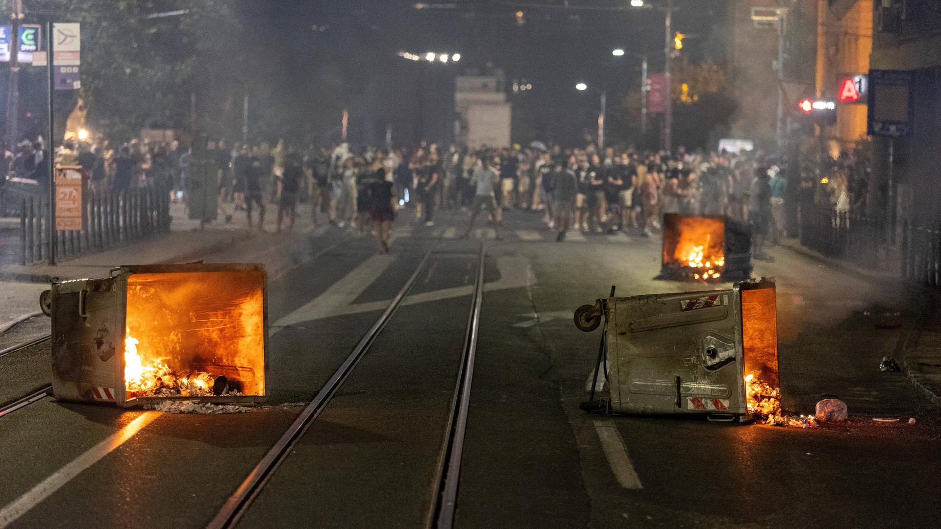 Bei einem Protest in Belgrad liegen mehrere brennende Mülltonnen auf der Straße.