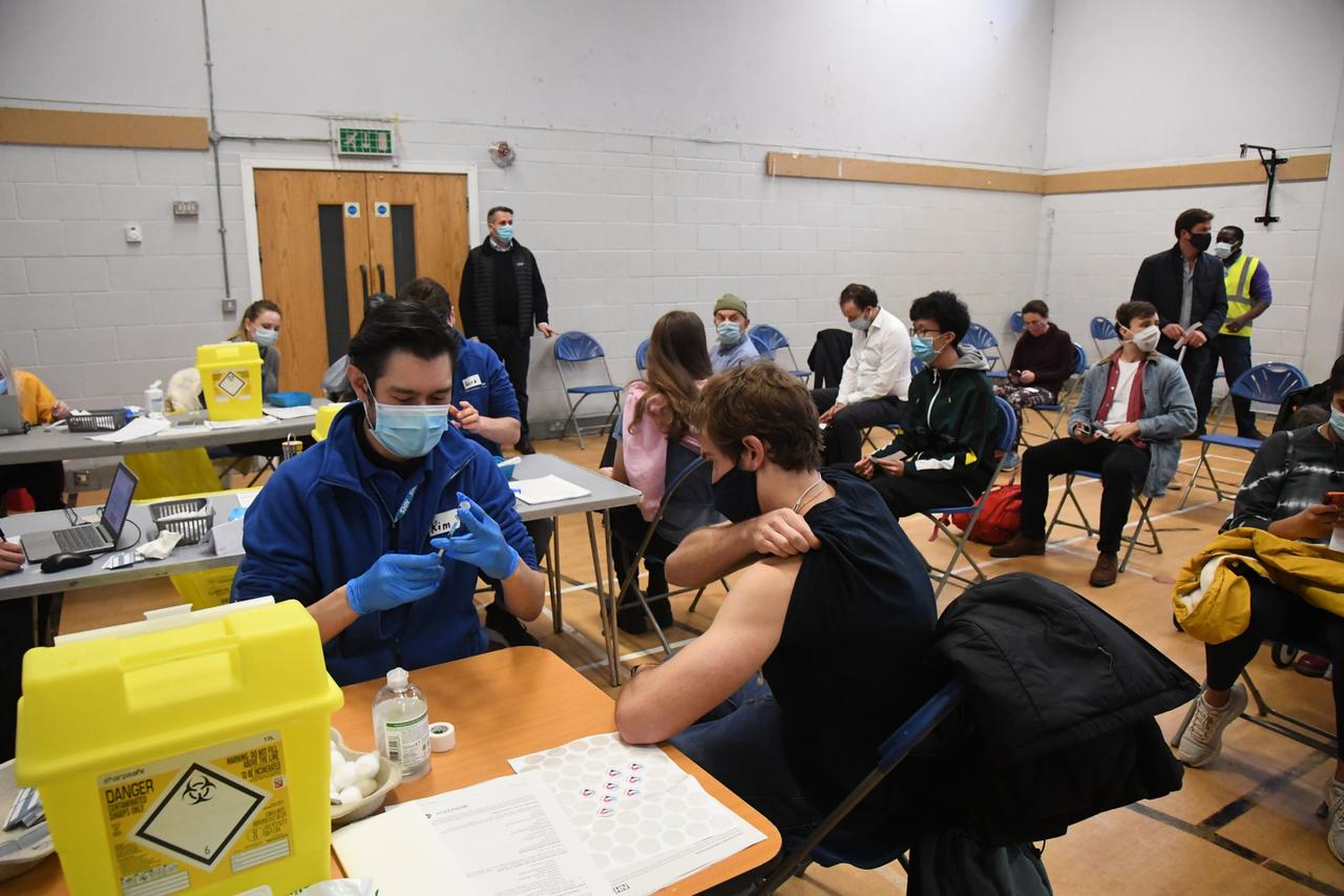 Großbritannien, London: Menschen sitzen im Stow Health Vaccination Centre, um eine Auffrischungsimpfung (Booster) gegen das Coronavirus zu erhalten.