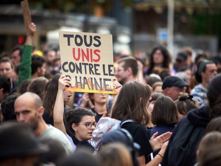 Eine Frau hält bei einer Demonstration am 1.7.2024 in Toulouse ein Schild mit der Aufschrift "Alle vereint gegen den RN".