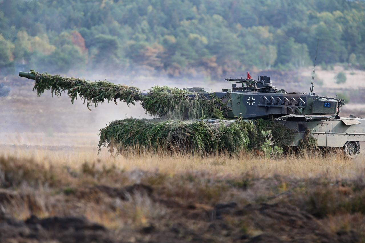 Ein Leopard-Panzer mit Tarnnetz fährt über einen Truppenübungsplatz