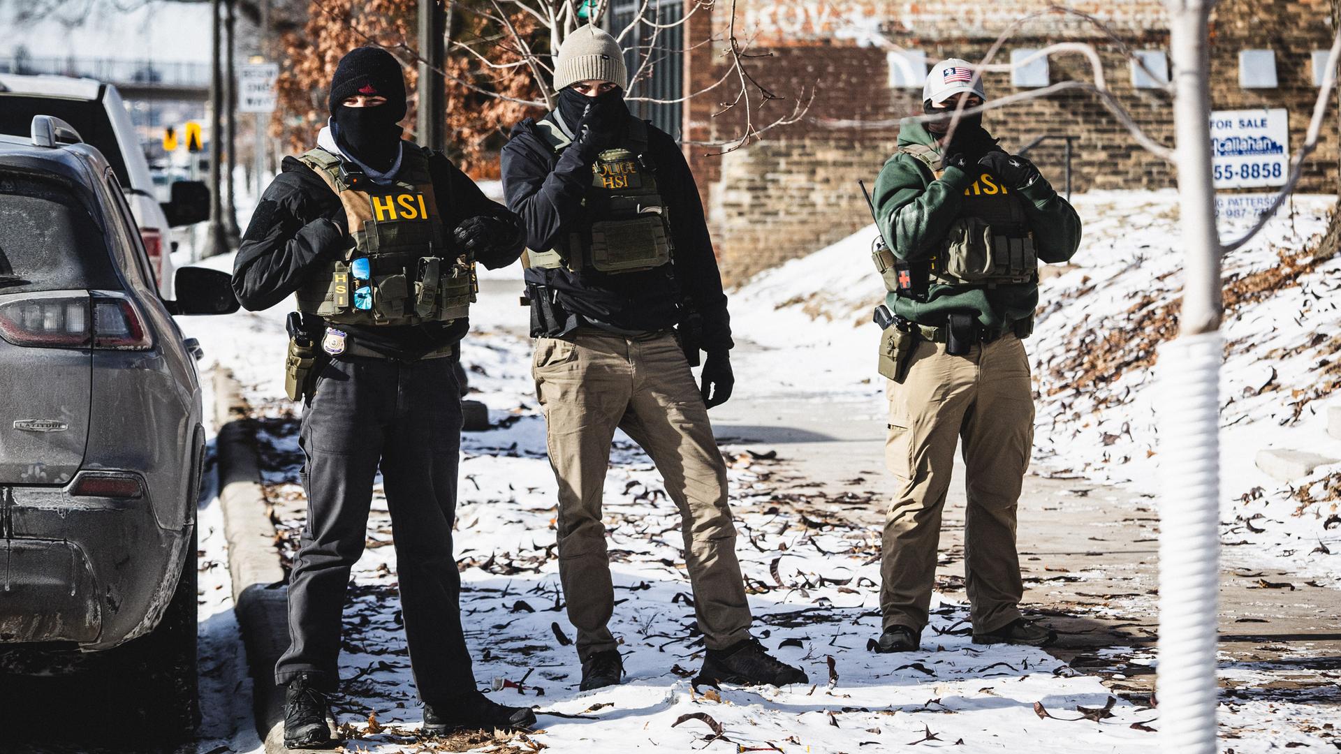 Beamte der Einwanderungs- und Zollbehörde ICE gehen in St. Paul, Minnesota, auf der Straße. 